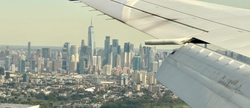 Looking out of a the Boeing 767 aircraft window to see the wingtip and a view of NYC skyline during the day. (certus)
