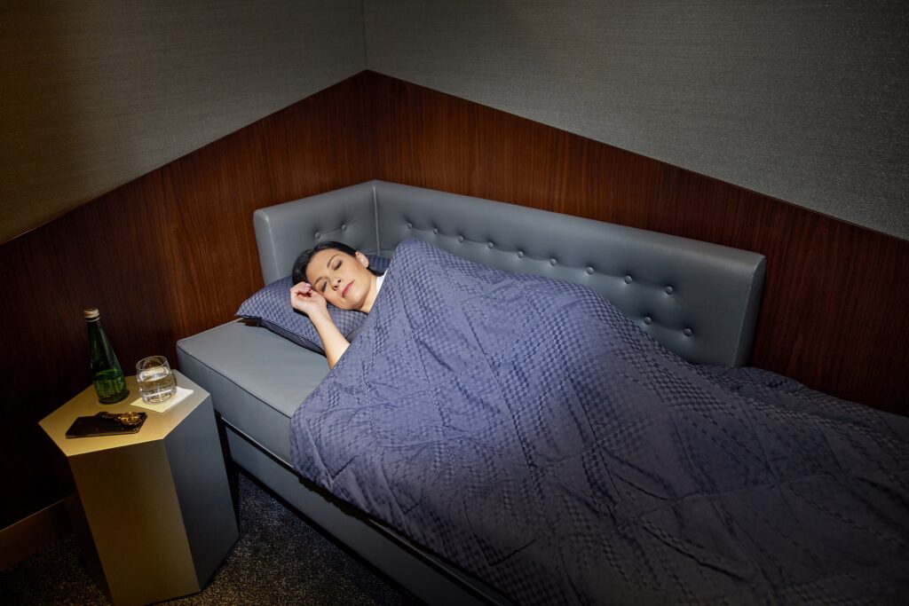 A woman is laying on a sofa bed having a nap.