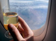 A passenger in Eurobiz raises his glass of champagne to the window, as the world passes below him.