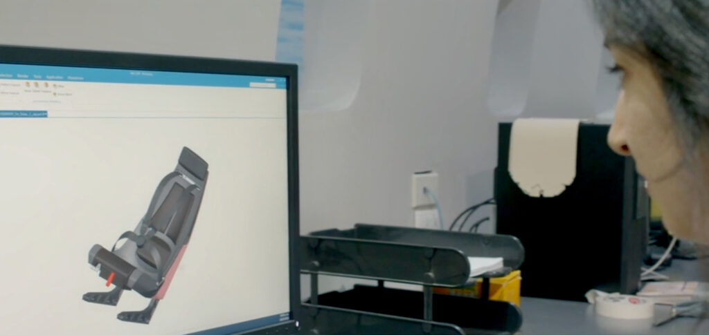 A female Soisa employee is looking at a aircraft seat rendering on the computer monitor. 