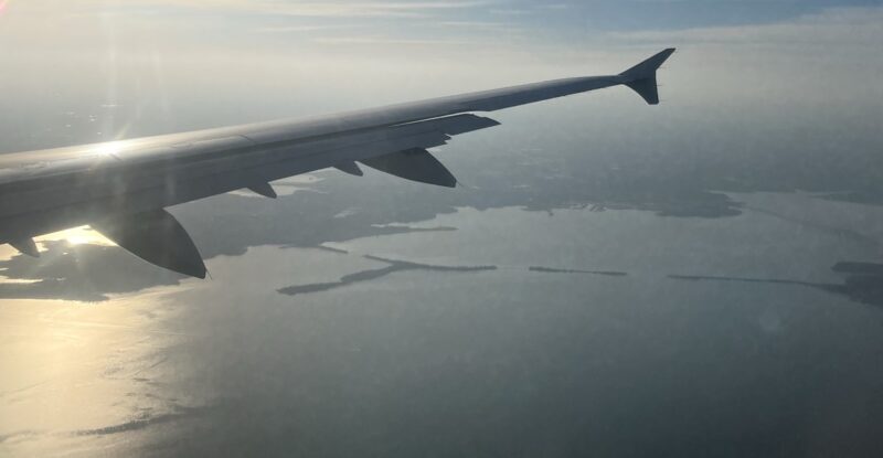 Aircraft flying into the sunset over a body of water