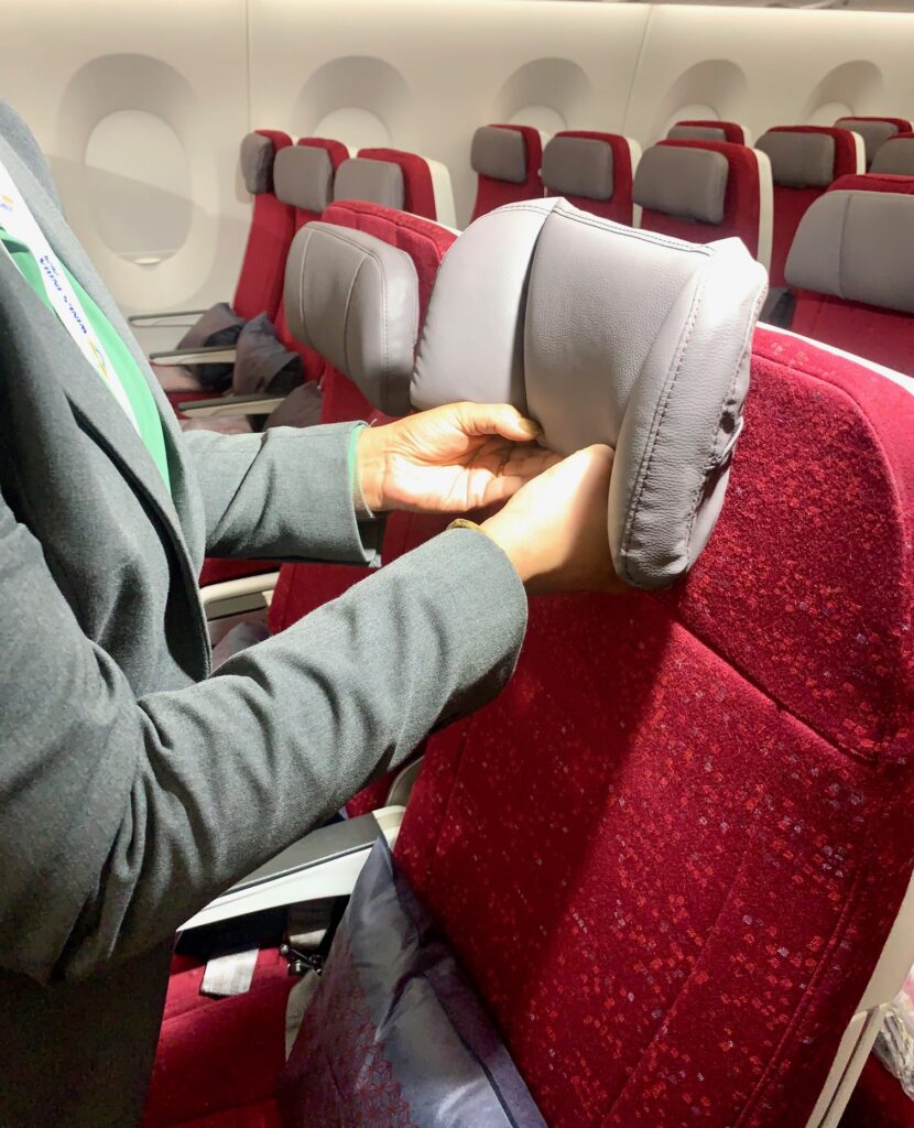 An Air India flight attendant is demonstrating the winged headrest. 