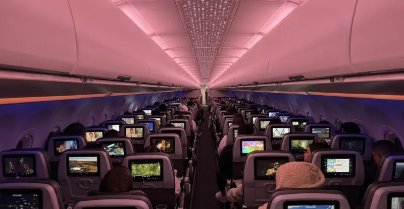 Inside a JetBlue A321neoLR: a view from the back of economy class, looking forward at passengers using their IFE screens.