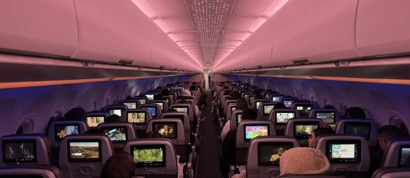 Inside a JetBlue A321neoLR: a view from the back of economy class, looking forward at passengers using their IFE screens.