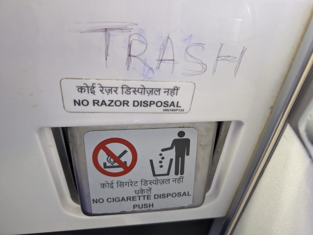 The word TRASH is etched on the lavatory wall above the trash bin on Air India aircraft.