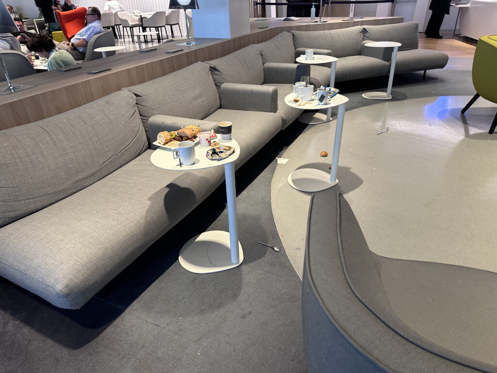 Tiny white tables needing to be cleaned in the Air France CDG L satellite business lounge