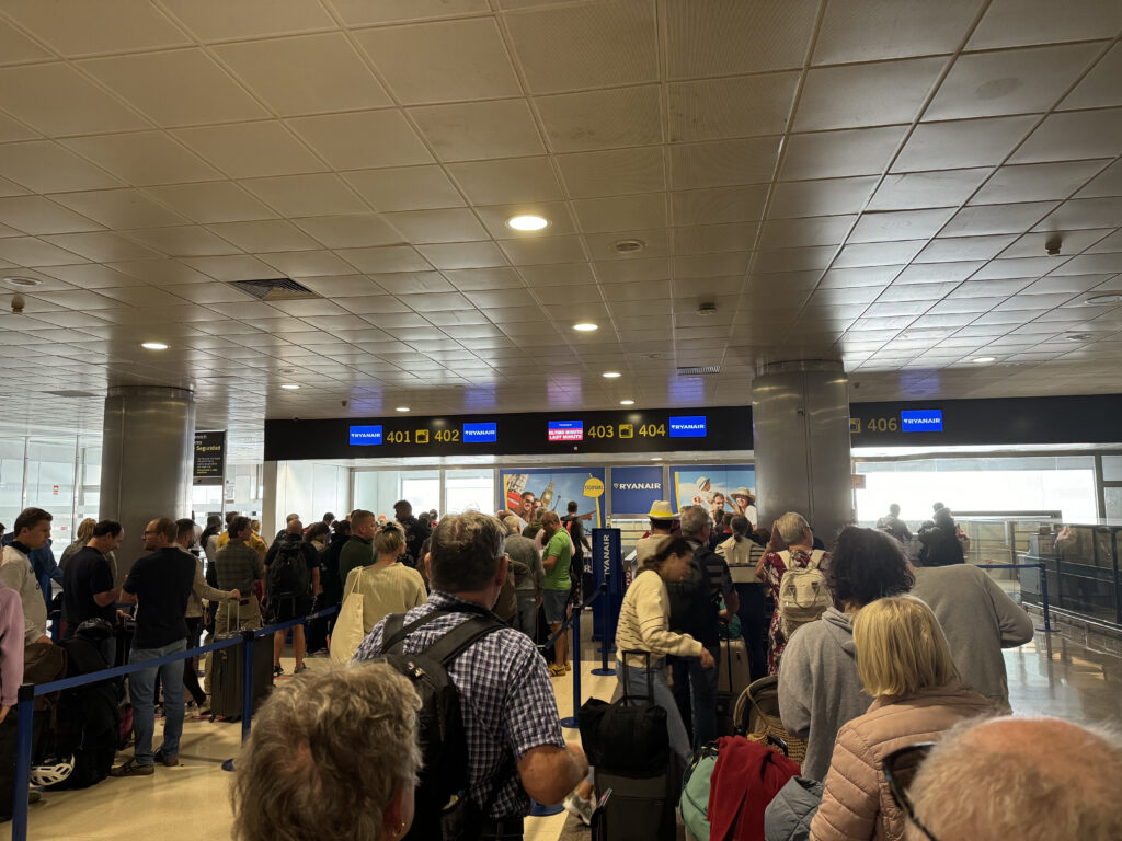 The bagdrop area at the airport is crowded with people.