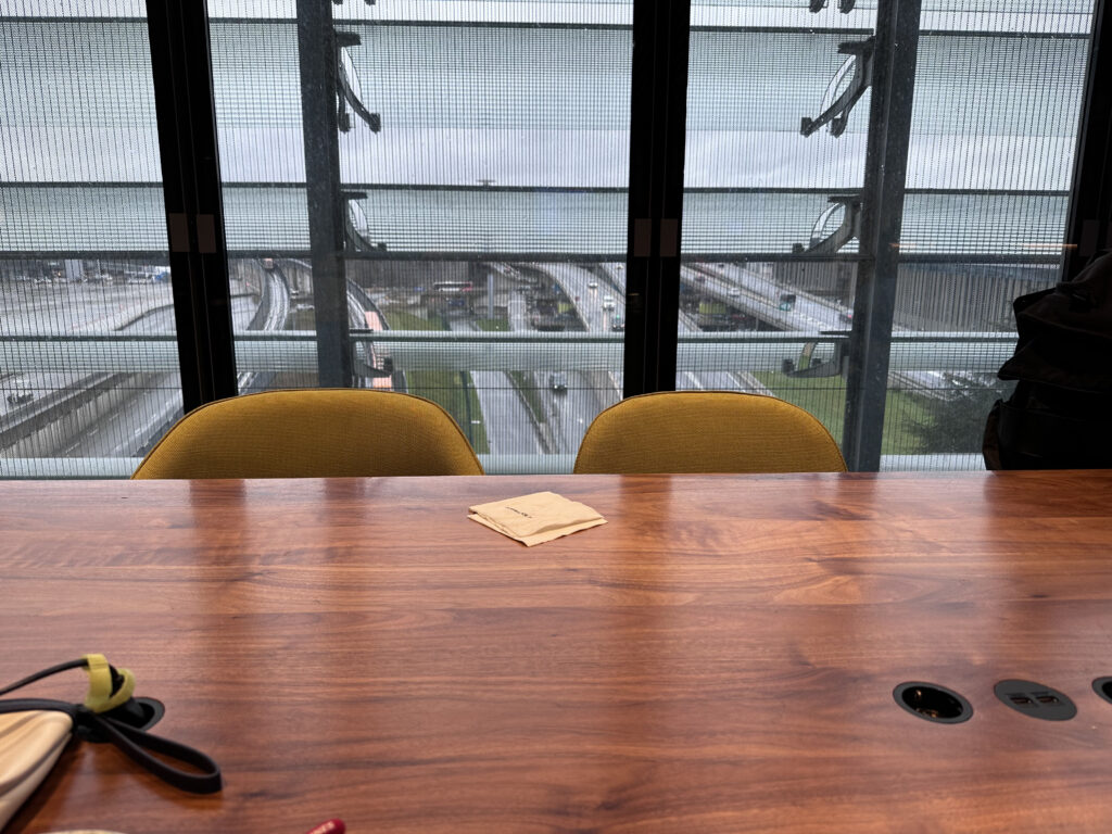 A large wooden table with chairs and a view of the airport roads.