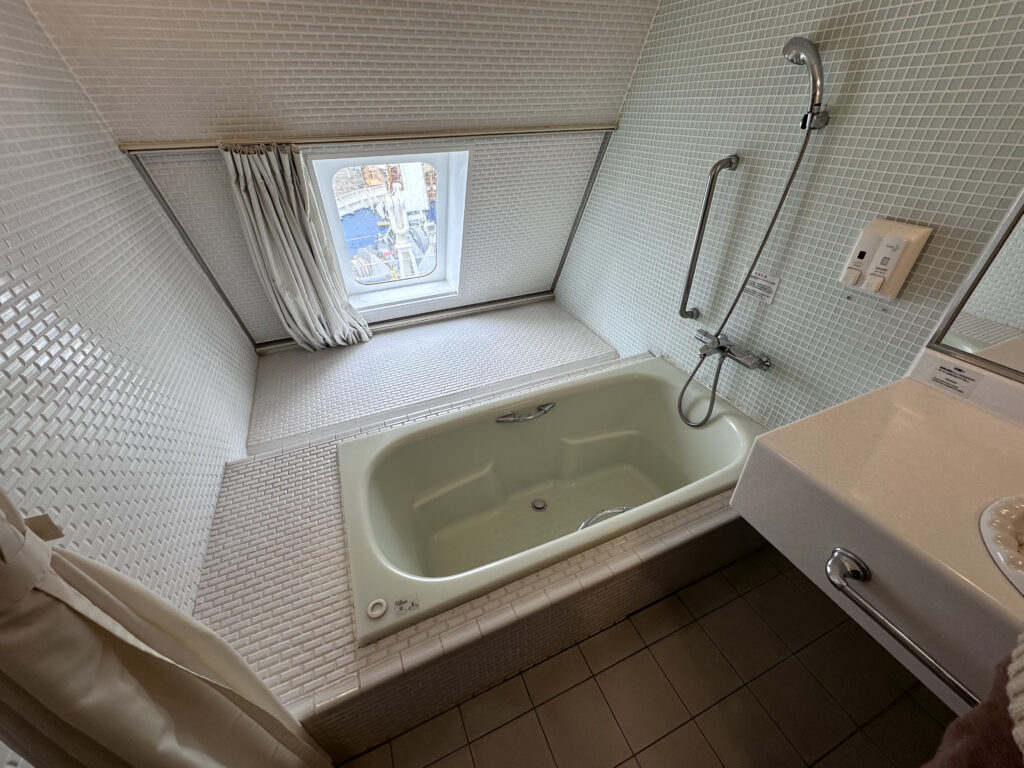 A window in the bathroom where there is a tub and a sink. The curtains have to be closed on the ferries at night.