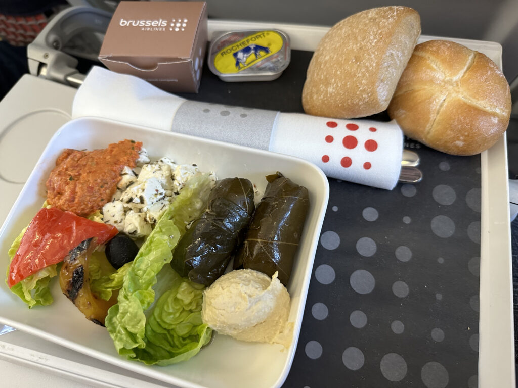 Chilled Mediterranean plate of food served with rolls and displayed on the aircraft tray table.