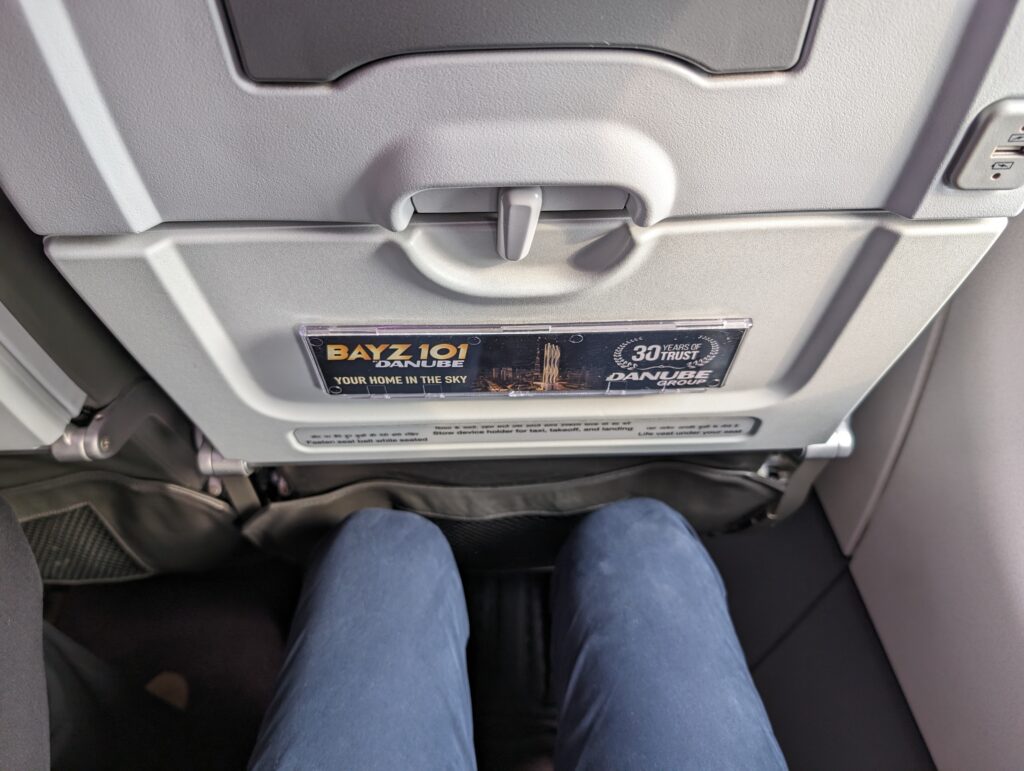 A man's knees are seen in close proximity to the Vistara seat in front of him. 