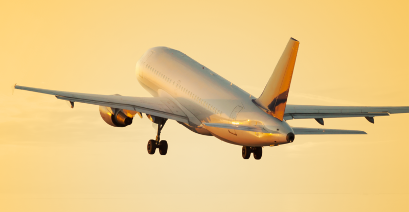 An aircraft is taking off into a brightly lit yellow sky. IT Spend report from SITA