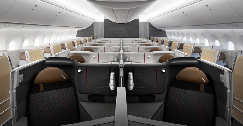 American Airlines Flagship Suite Preferred business class seats are seen in the foreground of the wider Flagship Suite cabin in greys and browns.