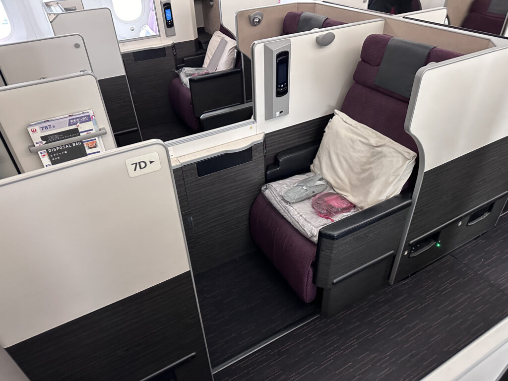 JAL business class 787 Collins Apex seat. The seat is a burgundy with grey detailing.