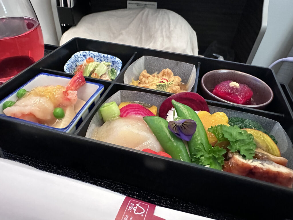 A colorful assortment of food being served in a bento box in-flight.