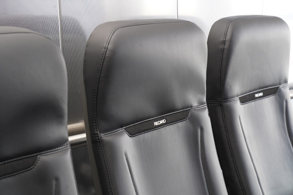 R Sphere by RECARO Aircraft Seating is an all grey slimline seat with the word RECARO on it.