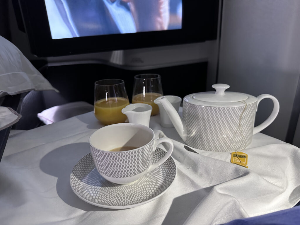 A white teapot and cup with saucer are set out on the tray table.