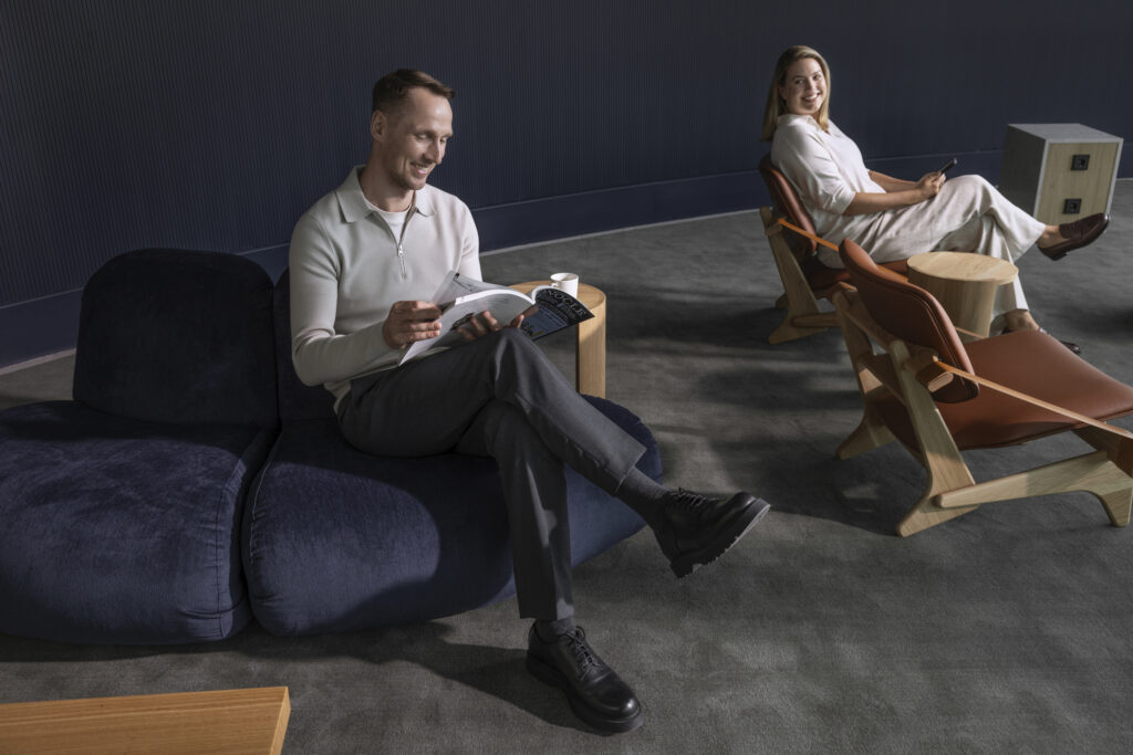 A man is sitting on a blue couch in the Schengen Lounge Platinum Corner