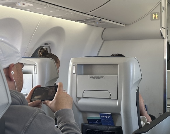 A passenger uses his connected device whilst seated in an Ascent recliner, part of the Nicest bundle offered on Breeze Airways' Airbus A220s.