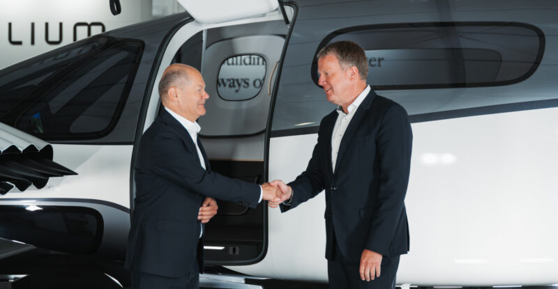 Two Lilium executives shake hands in front of the aircraft.