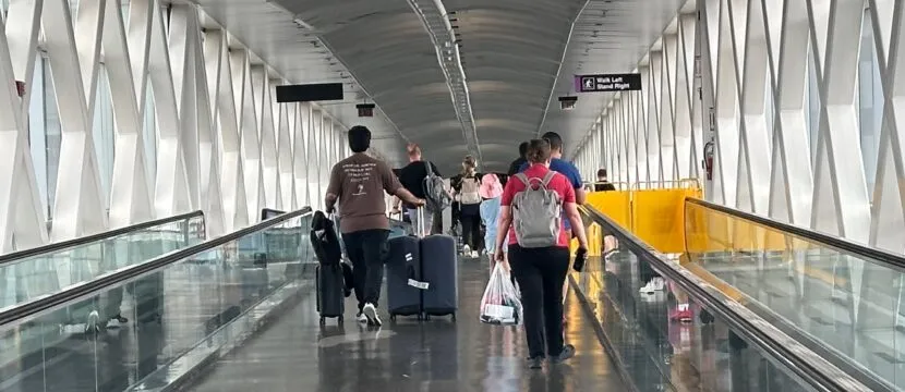 Travelers walk through the airport with their bags.