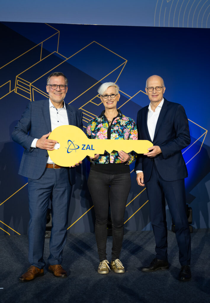 Anke Kaysser-Pyzalla, Peter Tschentscher, and Erster Bürgermeister are holding a large yellow ZAL key. Foto: Daniel Reinhardt/ZAL