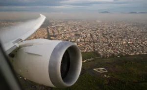 Looking out the AeroMexico aircraft over a city. The wing and engine are in view.