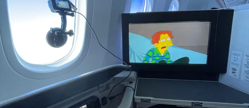 The in-seat IFE is playing the Simpsons whilst the author's camera is affixed to the window, capturing scenes outside.