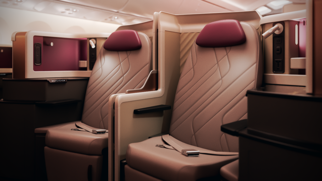 A center pair of business class seats in honeymoon configuration with the privacy wall down. The seats are a rich tan color with burgundy accents. 