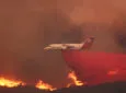 An aircraft dumping retardant on a fire in dramatic style. The red substance spews from the aircraft's belly,, dousing the fire raging below. Heavy smoke is in the air. Neptune Aviation Services is contracted to the US Forest Service. Here one of its BAe 146 jets is in action during 2016. The company just announced its intention to transition onto a fleet of modified Airbus A319 aircraft.