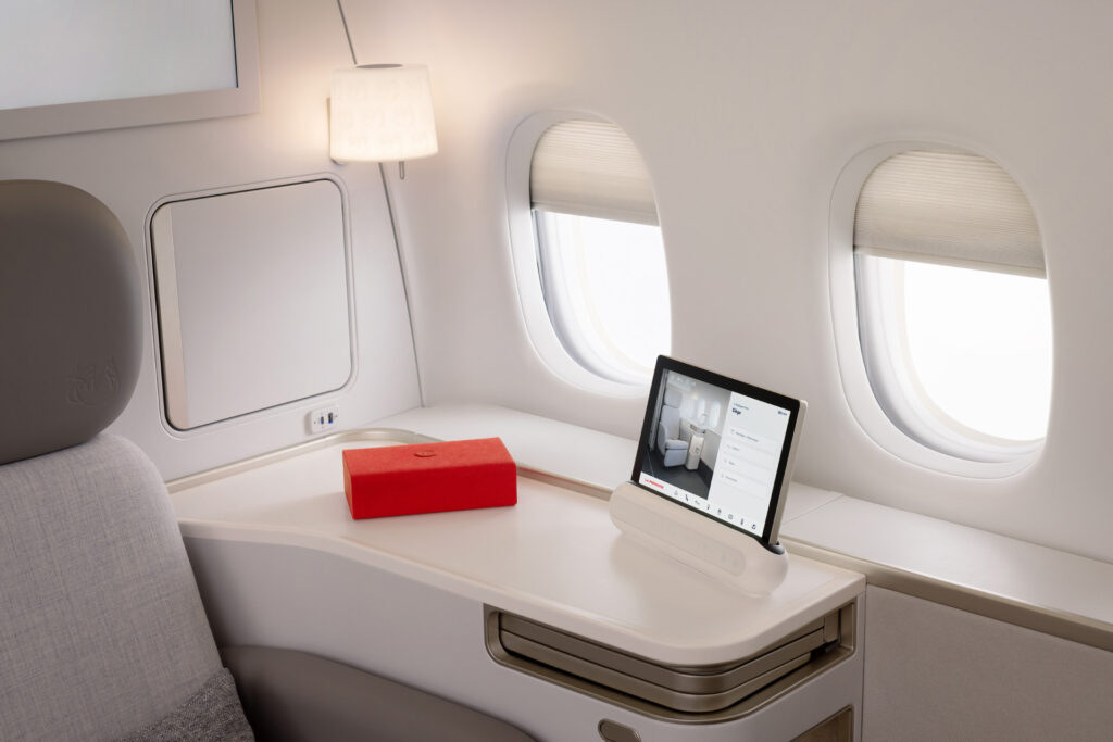 The armchair sit empty. A tablet and a red box sit atop the side table in the Air France first class suite.
