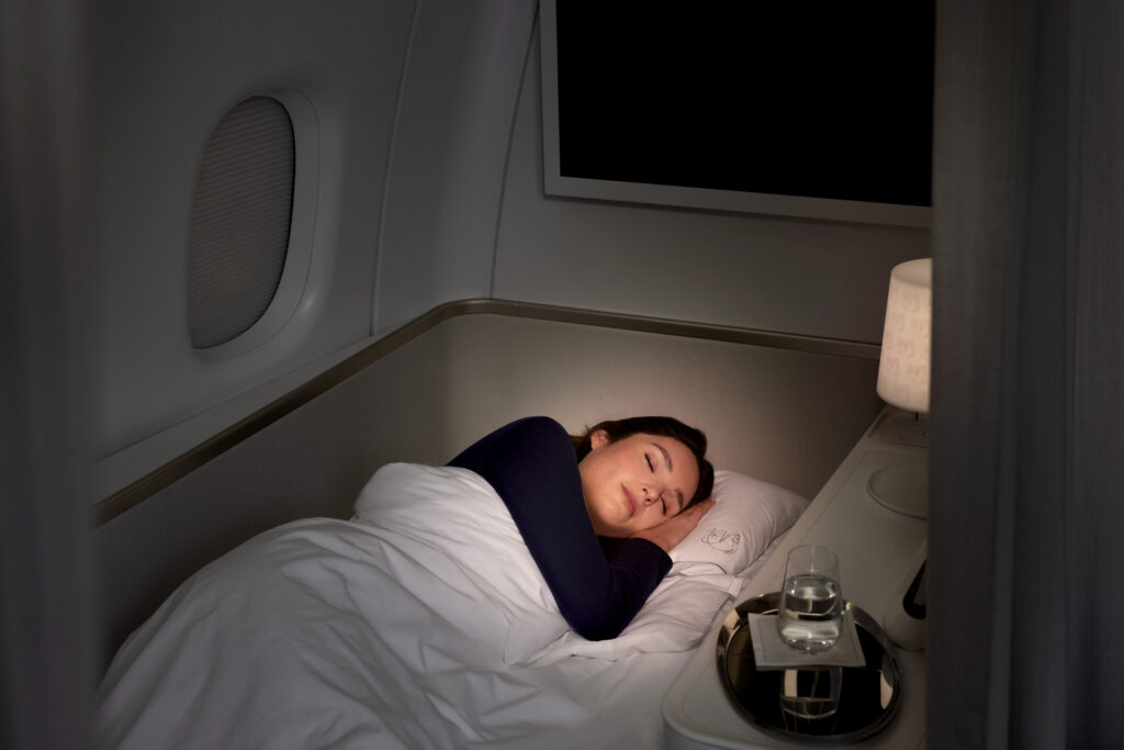 The chaise longue has been transformed into a bed aboard the Air France 777. A woman passenger is asleep on it. A small lamp is beside her head.