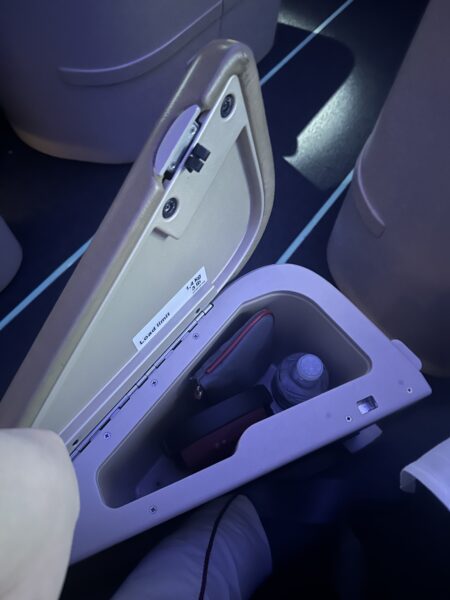 Storage well in the armrest of the aisle side of the seat.