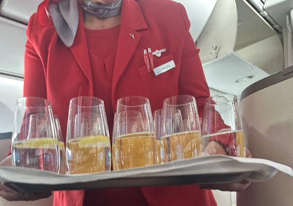 Austrian flight attendant carrying a tray of pre-flight drinks