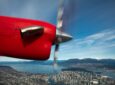 Harbour Air red prop engine as seen from inside the aircraft in flight over Victoria Harbour