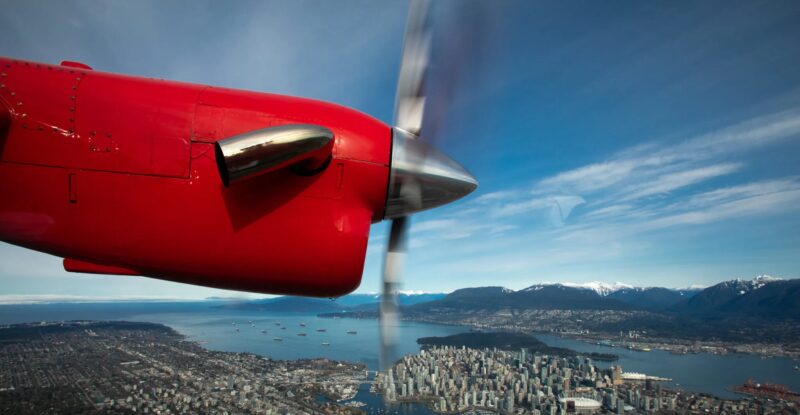 Harbour Air red prop engine as seen from inside the aircraft in flight over Victoria Harbour