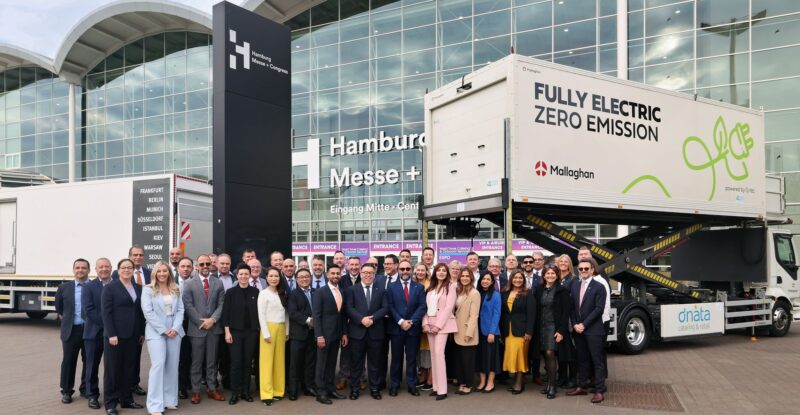 A large group of employees from Mallaghan and dnata are standing in front of a catering truck