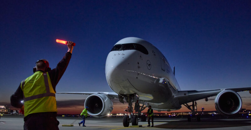 A ramp agent is guiding the Lufthansa A350-900 at Frankfurt.