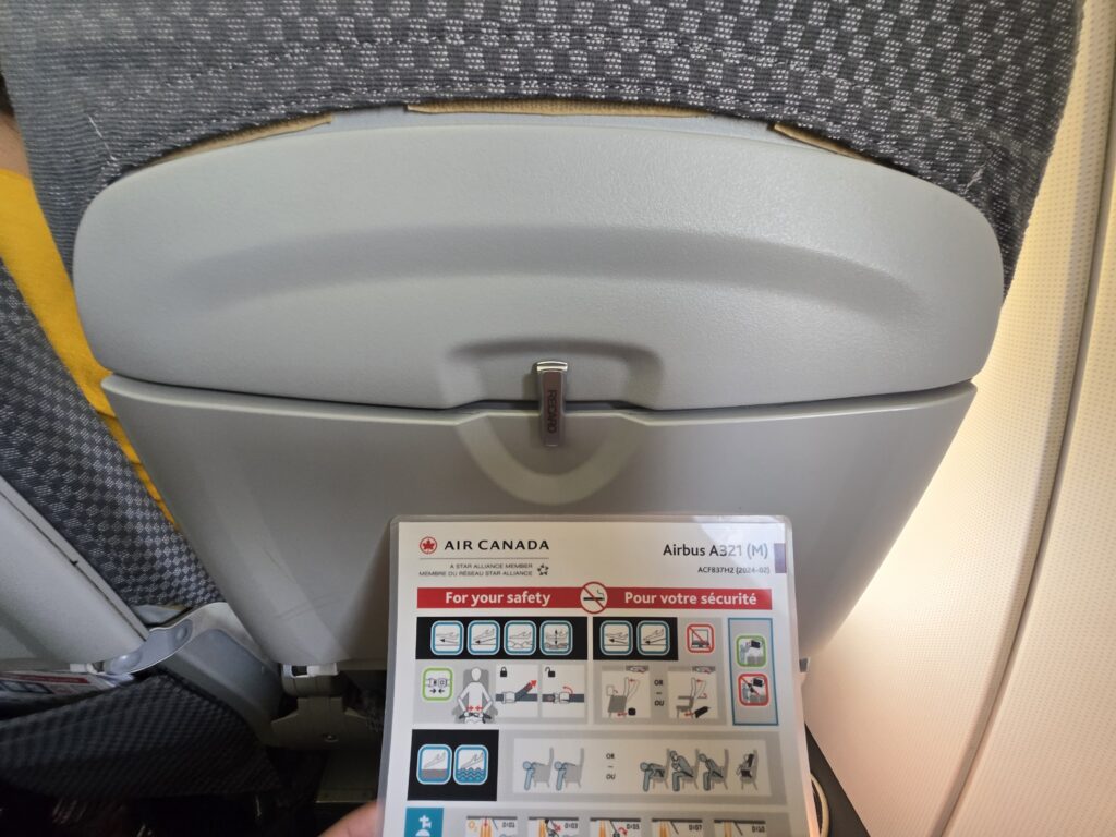 Seatback with no USB port. Air Canada A321 safety card is also in view.