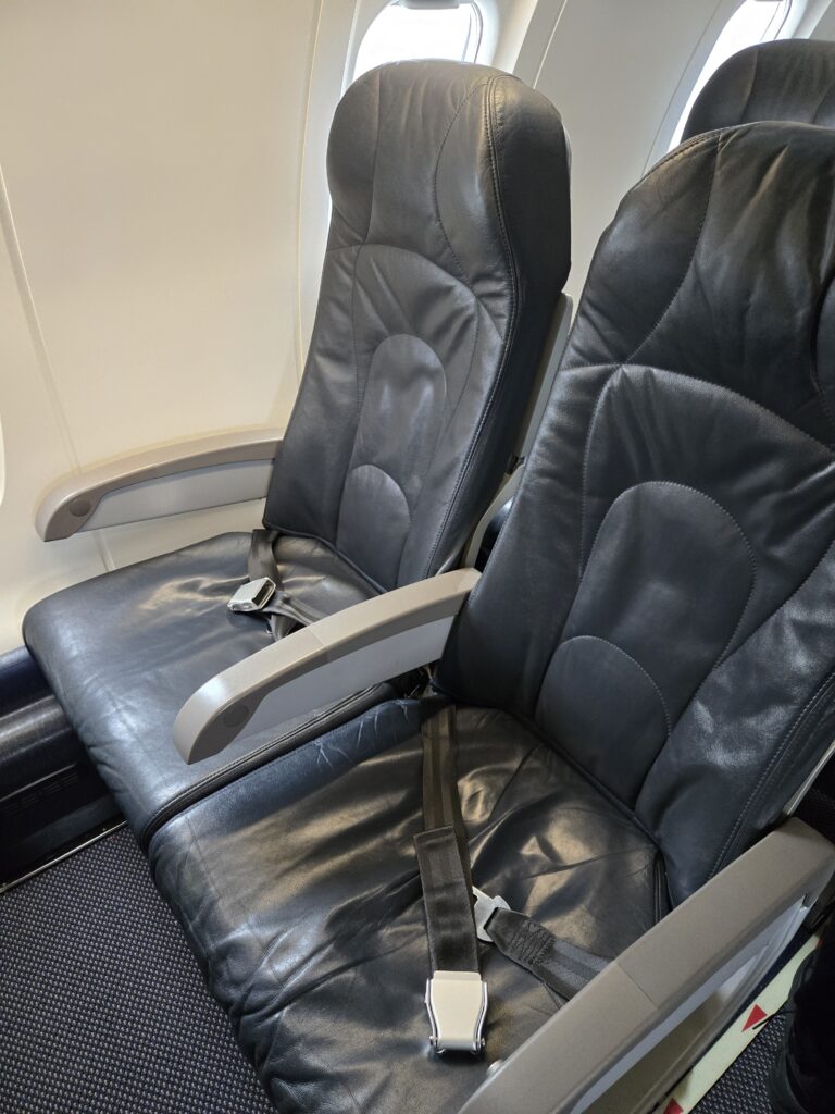 Two seats on the CRJ900, with seat belts laying atop them