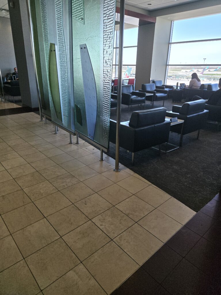 A empty lounge after lunch with plush seats and floor to ceiling windows.