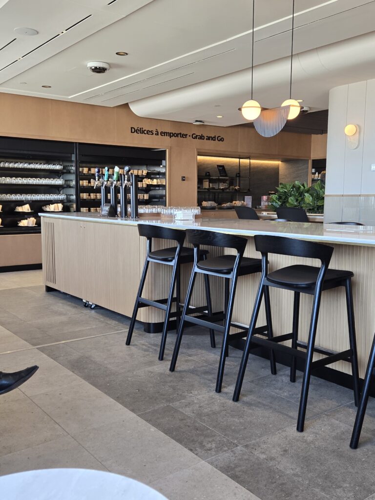 A view of high top tables and stools, and a glimpse of the hot food area in the back corner