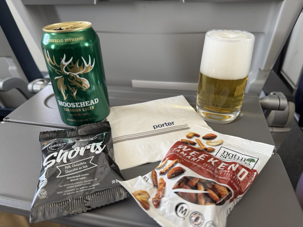 Snacks and beer sit on the aircraft tray table