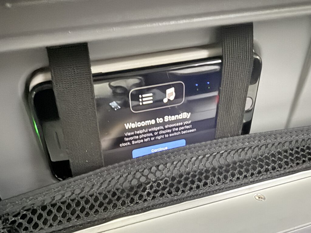 A smart phone is secured in a cubby with thick elastic bands.
