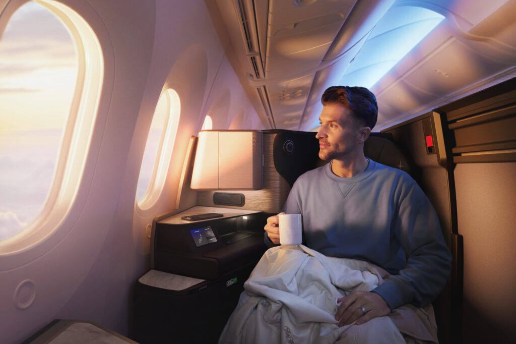 A man enjoys a mug of coffee in the Polaris Studio seat while looking out the aircraft window