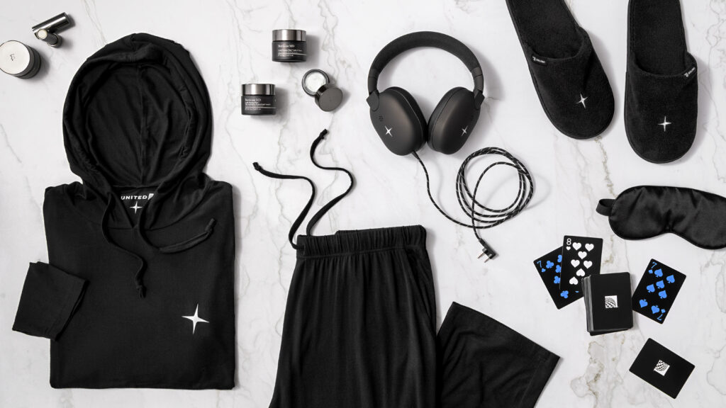 United Polaris Studio soft products are laid out, and include PJs, headphones, slippers, playing cards and skincare products from the amenity kit.