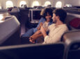 A man and woman are talking next to each other in their LATAM Premium Business seat