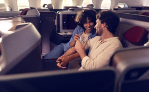 A man and woman are talking next to each other in their LATAM Premium Business seat