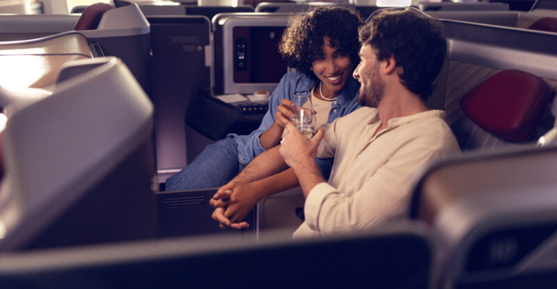A man and woman are talking next to each other in their LATAM Premium Business seat