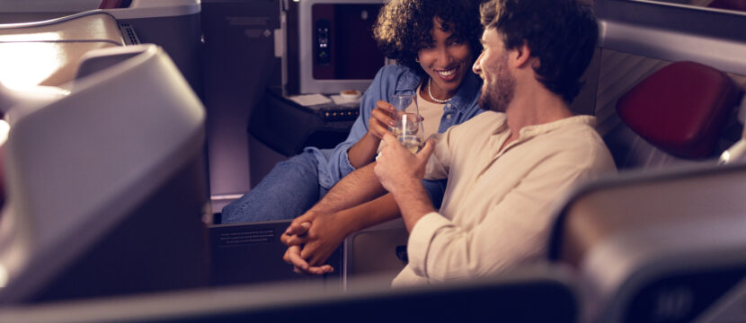 A man and woman are talking next to each other in their LATAM Premium Business seat